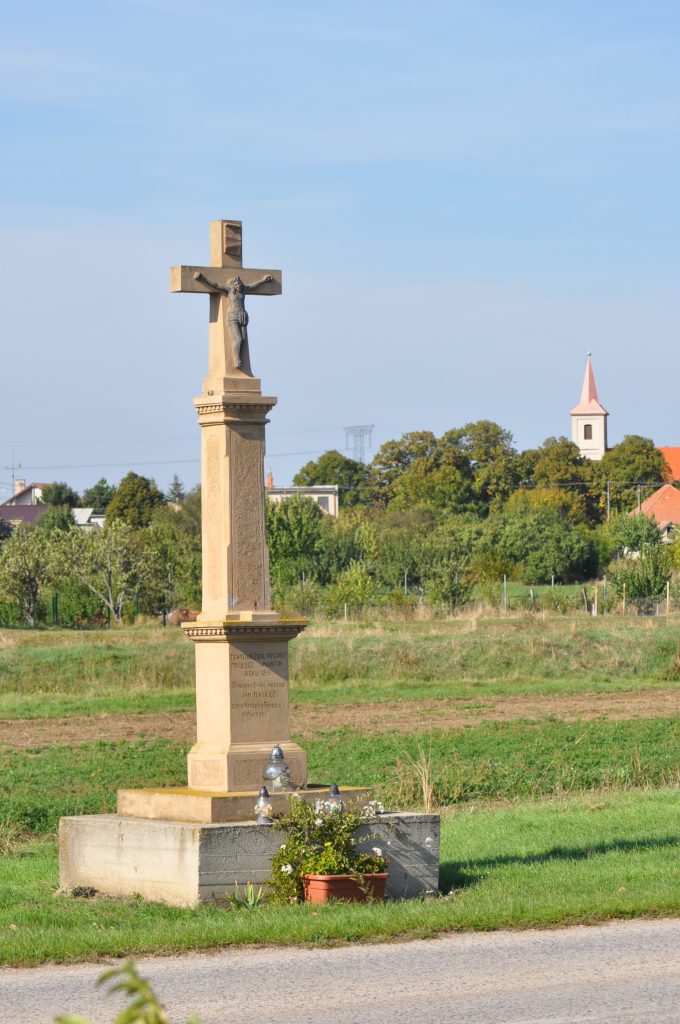 Út menti feszület, a háttérben a római katolikus templommal, Húl (Liszka József felv., 2021)