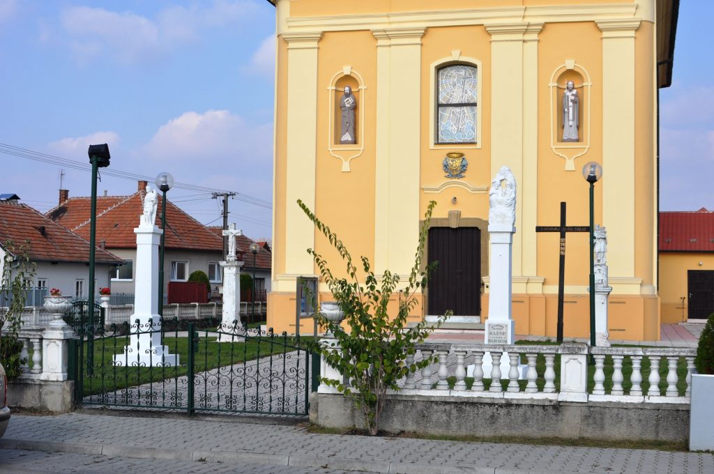 A Szentháromság-szobor a templomkertben, további szakrális kisemlékek társaságában, Zsitvafödémes (Liszka József felv., 2014)
